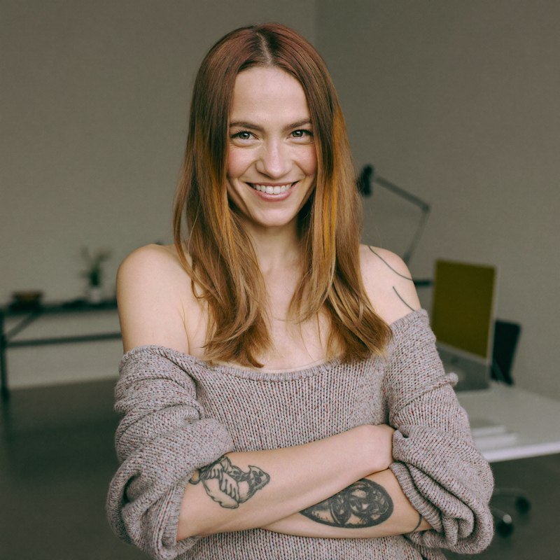 White woman with tattoos in a knit sweater, early-stage founder